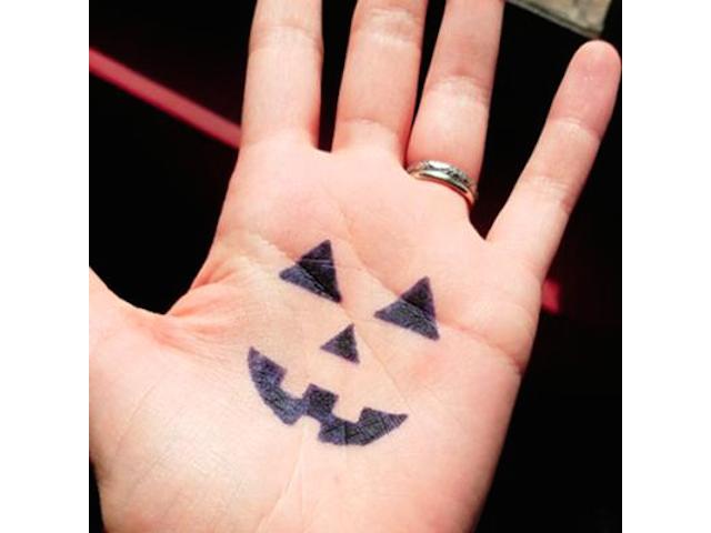 Spooky pumpkin face on hand